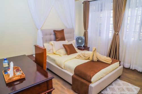 um quarto com uma cama grande, uma secretária e uma mesa em Villa Winga Deluxe Hotel em Kisumu