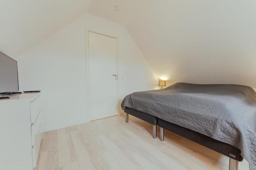 a white bedroom with a bed and a television at New Boat House in Leirvík