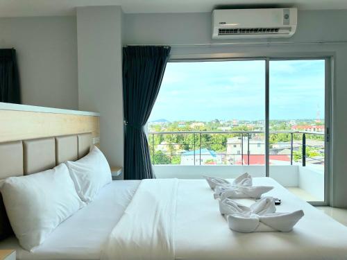 um quarto com uma cama branca e uma grande janela em Sun Inn em Songkhla