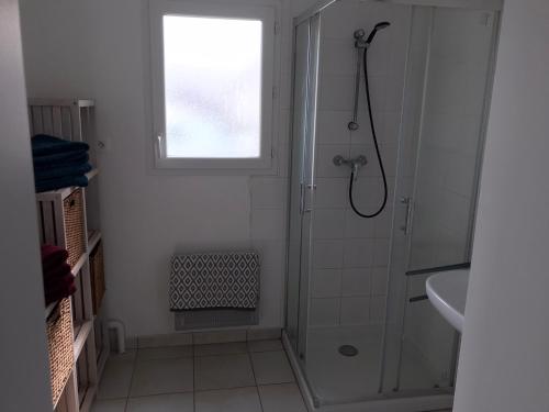 baño blanco con ducha y lavamanos en Appartement + Jardin, en Fouesnant