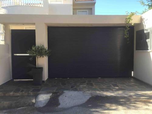 a black garage door with a potted plant in front of it at Ερέτρια ~Ένας προορισμός μια ανάσα από την Αθήνα in Eretria