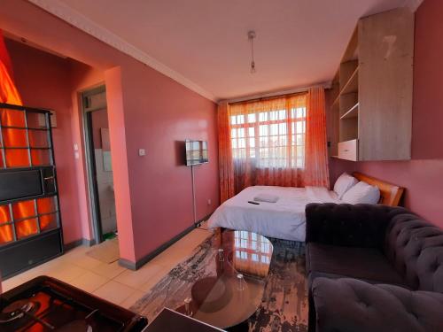 a living room with a bed and a couch at Pine Residency w Secure Parking, Wifi, Netflix & Rooftop Views in Kikuyu