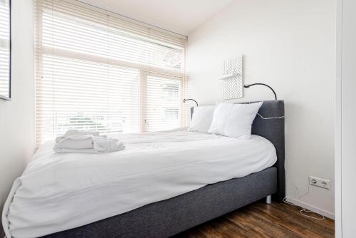 a bedroom with a large white bed with a window at De Schelp 85 in Zandvoort