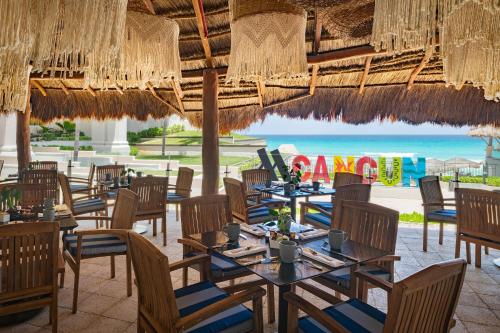 a restaurant with tables and chairs and the beach at Marriott Cancun, An All-Inclusive Resort in Cancún