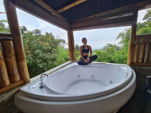 a woman sitting on the edge of a bath tub at Finca Colibrí Zafiro, Altos del Rosario in Cali