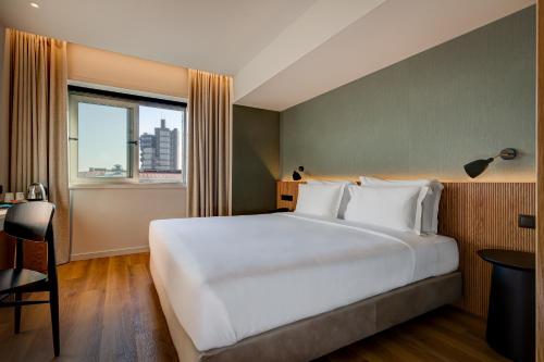 Un dormitorio con una gran cama blanca y una ventana en Acta The Clover, en Oporto