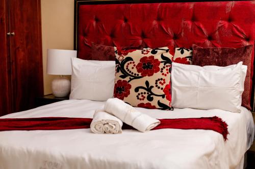 a bedroom with a bed with red and white pillows at TDM's Boutique Guest House in Pretoria