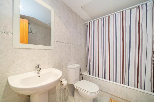 W łazience znajduje się umywalka, toaleta i lustro. w obiekcie Beach and Green w Alicante