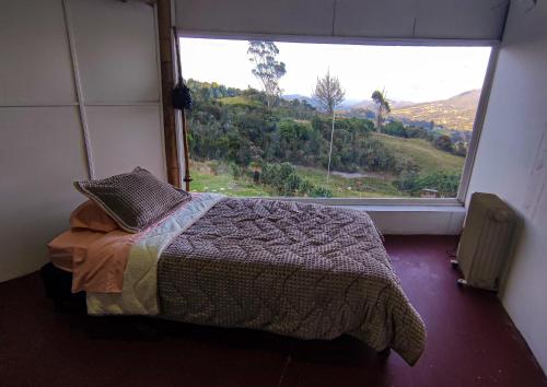 1 dormitorio con cama y ventana grande en Bio Casa Colibrí, en Bogotá