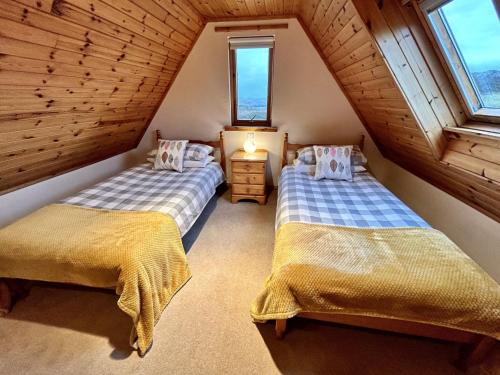 two beds in a attic room with two windows at Myrtle Cottage in Lairg