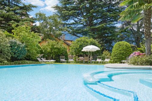 uma piscina num quintal com cadeiras e árvores em Hotel Sonnenhof em Merano