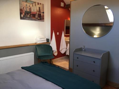 1 dormitorio con cama, espejo y silla en La Mirabelle, en Saint-Pierre-de-Fursac