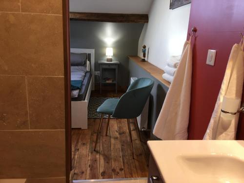 a bathroom with a sink and a chair in a room at La Mirabelle in Saint-Pierre-de-Fursac