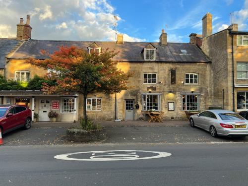 an old building with two cars parked in front of it at Siam cottage guesthouse over 300 years old with Thai restaurant in Moreton in Marsh