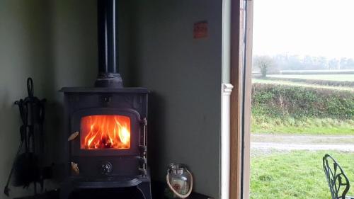 a fireplace with a fire in it next to a window at Hut Haf in Talacre