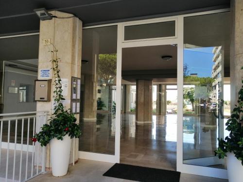 eine Glastür in einem Gebäude mit zwei Topfpflanzen in der Unterkunft Appartamento vista mare in Lido di Jesolo