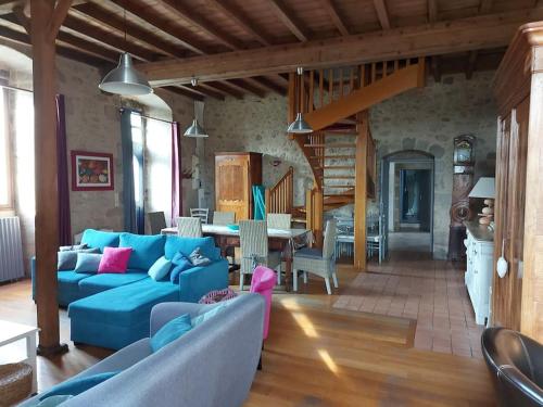 un salon avec un canapé bleu et une salle à manger dans l'établissement La Commanderie Grand Gite 10kms " Puy duFou", à Mauléon