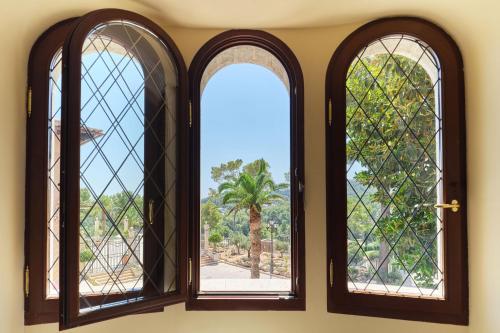 two windows in a room with a view of a palm tree at Castillo Hotel Son Vida, a Luxury Collection Hotel, Mallorca in Palma de Mallorca
