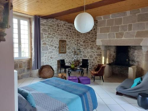 - une chambre avec un lit et une cheminée en pierre dans l'établissement La Commanderie Grand Gite 10kms 