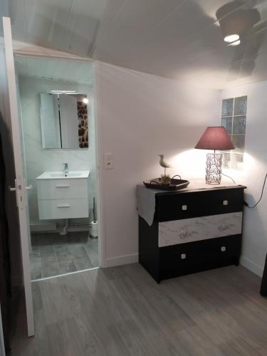 een badkamer met een wastafel en een bureau met een lamp bij La maison D'Orée in Polignac