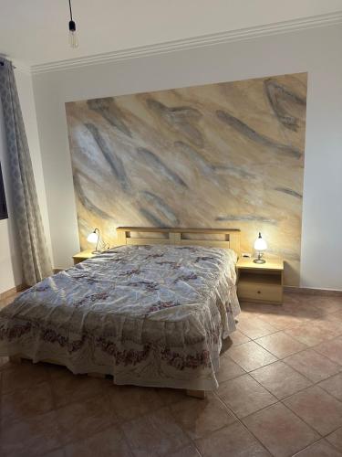 1 dormitorio con 1 cama y una pintura en la pared en Villetta Forestaforte, en Leuca