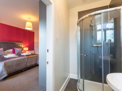 a bathroom with a shower and a bed and a sink at Vicarsford Farmhouse with Hot Tub in Leuchars