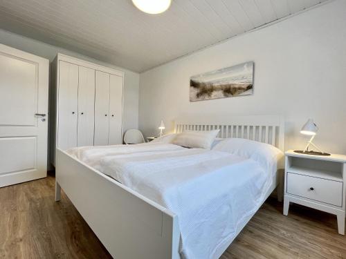a white bedroom with a large white bed in it at Gästehaus am Kampland - Wohnung 4 in Dahme