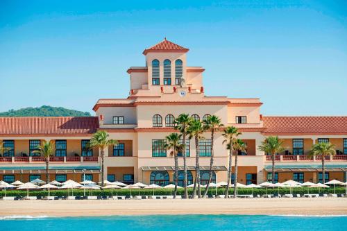 duży budynek z palmami przed nim w obiekcie Le Meridien Ra Beach Hotel and Spa w mieście El Vendrell