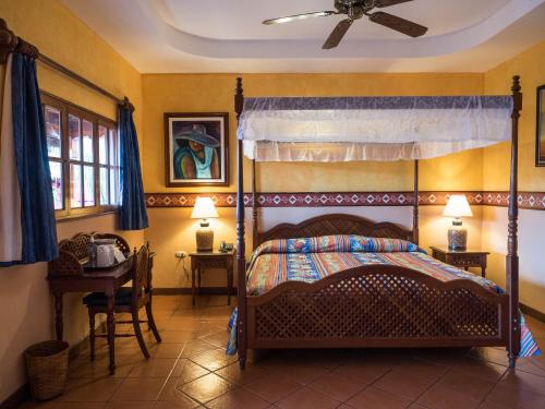 a bedroom with a canopy bed and a table at Hotel Colonial Granada in Granada