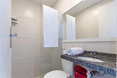 W łazience znajduje się umywalka, toaleta i lustro. w obiekcie Beach Townhouses #C12 - Tríplex por Carpediem w mieście Aquiraz