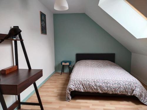 een slaapkamer met een bed en een bureau op zolder bij Charmant appartement au calme avec parking in Besançon