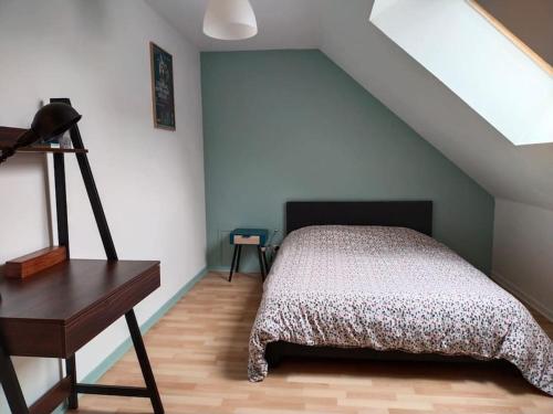 sypialnia z łóżkiem i biurkiem na poddaszu w obiekcie Charmant appartement au calme avec parking w Besançon