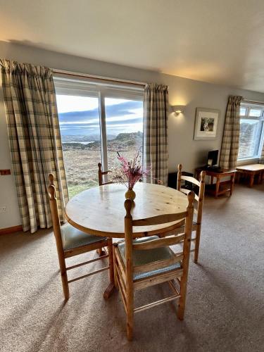 a dining room with a table and chairs and a window at Orchid Cottage in Lairg