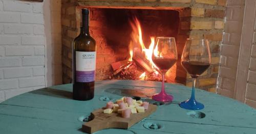 a bottle of wine and two glasses on a table with a fireplace at Entre Nubes in Los Hornitos