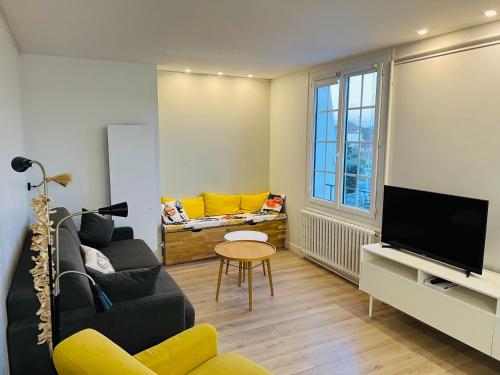a living room with a couch and a tv at Bel appartement plein centre 100m de la mer in Merville-Franceville-Plage