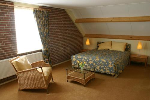 a bedroom with a bed and a chair and a window at De Kruumte in Giethoorn