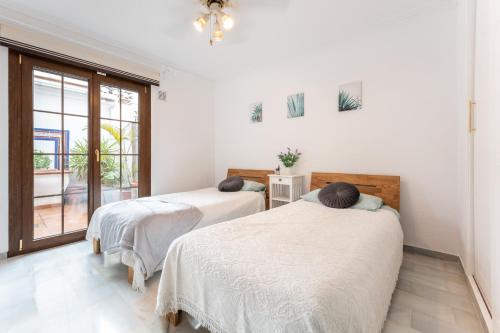 2 łóżka w białym pokoju z oknem w obiekcie MalagaSuite Mijas Golf Panoramic Views w mieście Mijas Costa