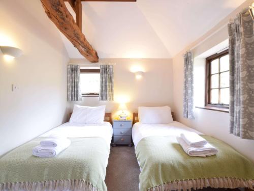 two twin beds in a room with two windows at The Stables in Colchester