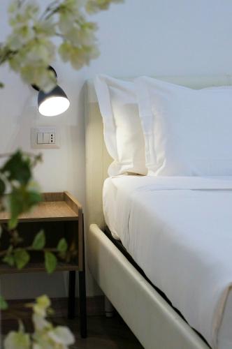 a bed with white sheets and pillows next to a table at The Roman Way San Giovanni in Rome