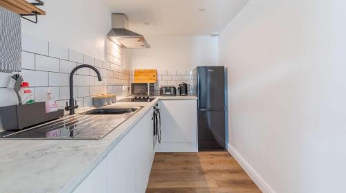 a kitchen with white counters and a black refrigerator at Brand New, Stunning, Central Old Town Balcony Flat in Hastings