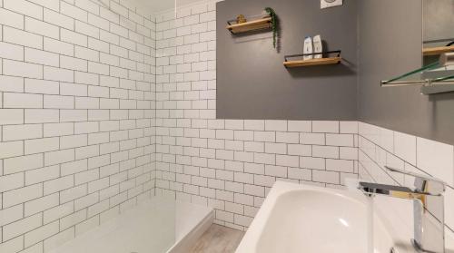 a white tiled bathroom with a tub and a sink at Brand New Central Balcony Flat - Hastings Holidays in Hastings
