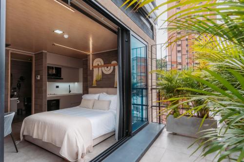 1 dormitorio con 1 cama en un balcón con plantas en Living by Armoniko, en Medellín