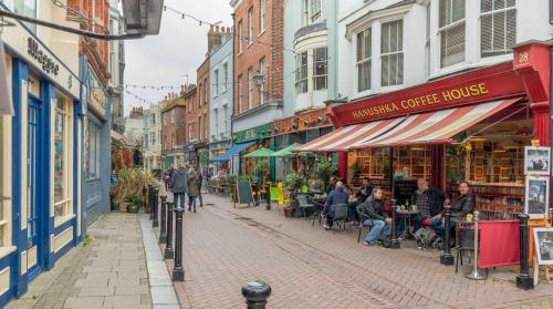 a street with people sitting at tables in front of stores at Brand New, Stunning, Central Old Town Balcony Flat in Hastings