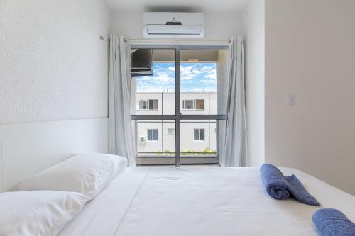 1 dormitorio con cama blanca y ventana en Beach Townhouses #C13 - Acomodação por Carpediem, en Aquiraz