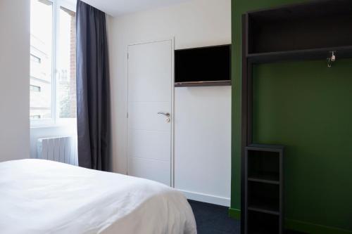 1 dormitorio con cama blanca y pared verde en Logis Hotel du Maine, en Laval