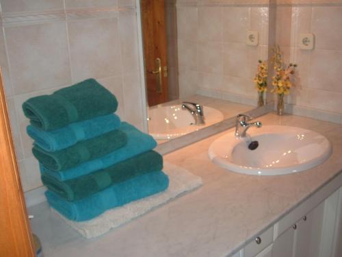 Baño con 2 toallas verdes en un lavabo en Ca del Pòsol en Durro