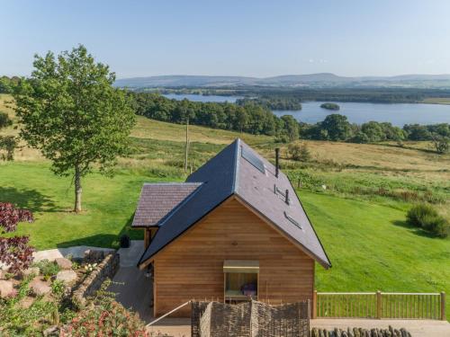 a small wooden house with a clock on the roof at Gamekeeper's Lodge- a cottage with a spectacular view in Port of Menteith