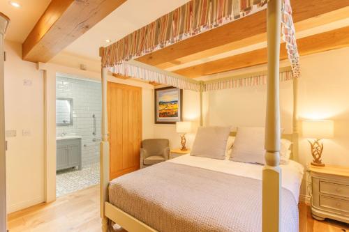a bedroom with a canopy bed and a bathroom at Gamekeeper's Lodge- a cottage with a spectacular view in Port of Menteith