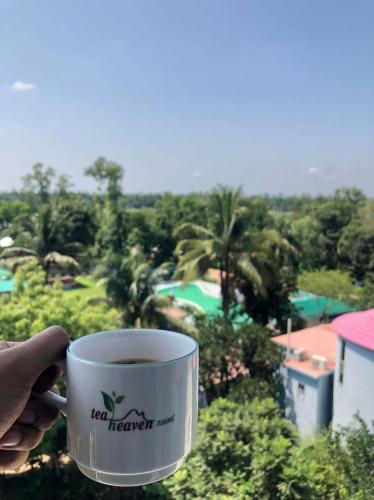 a person holding a cup of tea terner coffee at Tea Heaven Resort in Sreemangal