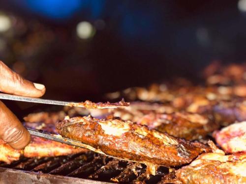 a person is cooking meat on a grill at Tea Heaven Resort in Sreemangal